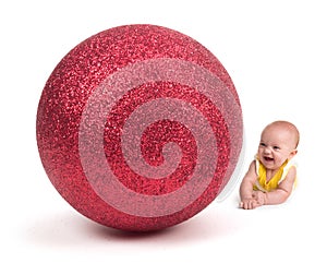 Cute Baby smiling at a Huge Christmas Ornament on white