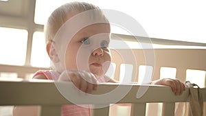 Cute baby standing in cot. Cute childhood. Toddler girl in crib