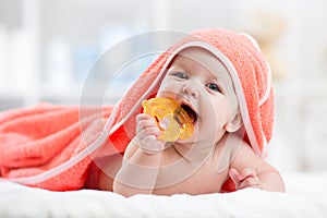 Cute baby with teether under a hooded towel after bath