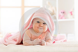 Cute baby with teether under a hooded towel after bath