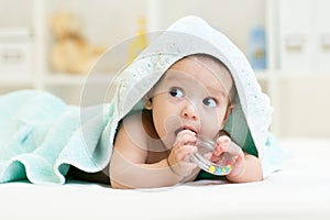 Cute baby with teether under towel indoor