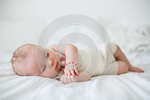 Cute baby toddler boy, sleeping with white and red bracelet
