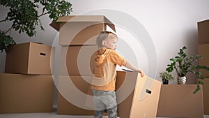 Cute baby toddler carries a cardboard box. The child helps his parents when moving to a new home. Real estate concept