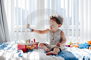 Cute baby toddler playing with learning multicolor toy pounding bench at home. Count learning.  Early age Montessori education.