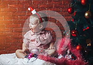 Cute baby with toys and Christmas tree on background. Holidays celebration concept