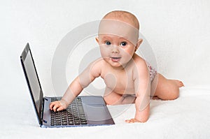 Cute baby typing on a laptop computer isolated on white