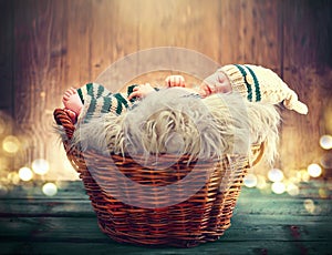 Cute baby wearing knitted funny costume, sleeping in a basket over wooden background