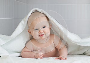 Cute baby in white bathing towel in bathroom