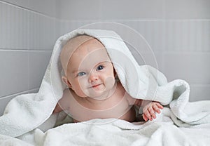 Cute baby in white bathing towel in bathroom