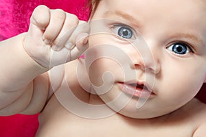 Cute baby with wide opened blue eyes, beautiful kid`s face and h
