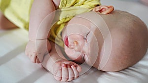 Cute baby in yellow clothes sleeping in white crib.