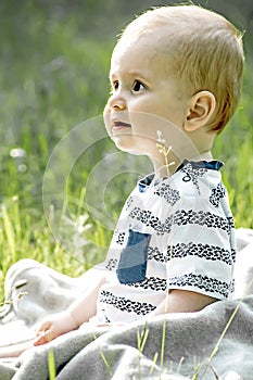 Cute bady boy looking surprised with big beautiful eyes sitting on grass outdoor on nature