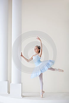 A cute ballerina in ballet costume and in pointe dances near the mirror. Girl in the dance class. The girl is studying ballet. Bal