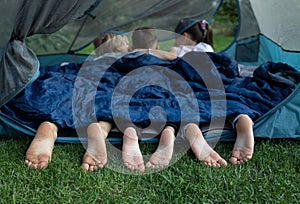 cute bare feet of three children peeking out of a sleeping bag