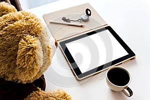 Cute bear doll watching taplet on table