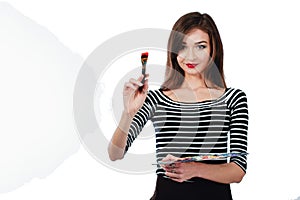 Cute beautiful girl artist holding a palette and brush in the process draws inspiration. White background, isolated.