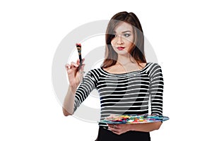 Cute beautiful girl artist holding a palette and brush in the process draws inspiration. White background, isolated.