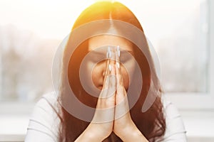 Cute beautiful girl folded her hands in prayer. A woman asks God for help