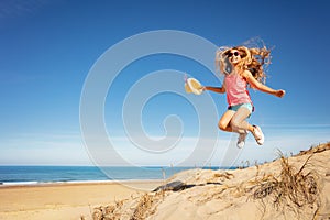 Cute beautiful girl with straw hat jump over beach