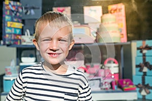 Cute beautiful happy little boy smiling in front of shop-window