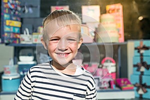 Cute beautiful happy little boy smiling in front of storefront