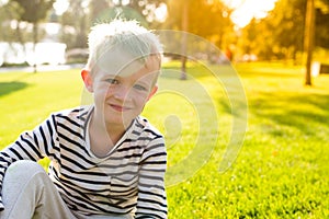 Cute beautiful happy smiling little boy sit on grass looking at camera