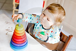 Cute beautiful little baby girl playing with educational toys at home or nursery, indoors. Happy healthy child having