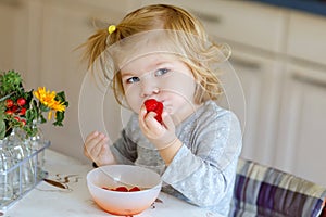 Cute beautiful little toddler girl eating fresh raspberries. Adorable baby child tasting raspberry. Healthy food