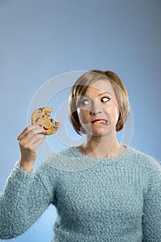 Cute beautiful woman with chocolate stain in mouth eating big delicious cookie