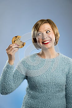 Cute beautiful woman with chocolate stain in mouth eating big delicious cookie