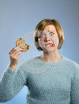 Cute beautiful woman with chocolate stain in mouth eating big delicious cookie