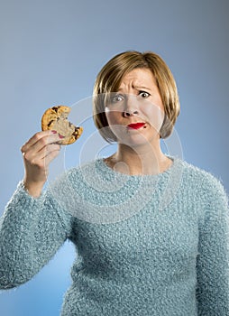 Cute beautiful woman with chocolate stain in mouth eating big delicious cookie