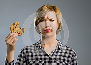 Cute beautiful woman with chocolate stain in mouth eating big delicious cookie