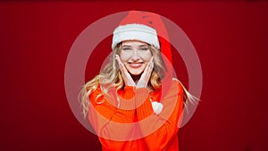 a cute beautiful woman in a Santa Claus hat on a red background.