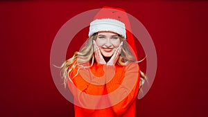 a cute beautiful woman in a Santa Claus hat on a red background.