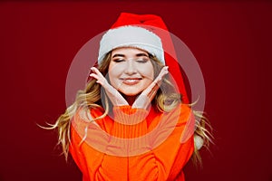 a cute beautiful woman in a Santa Claus hat on a red background.