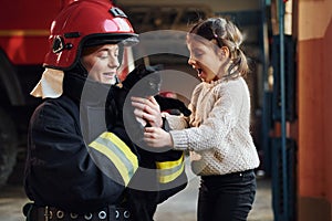 Cute black cat. Happy little girl is with female firefighter in protective uniform