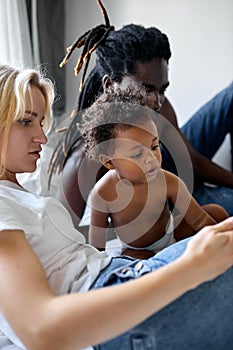 cute black daughter child have fun with parents watching video on smartphone