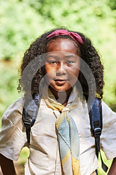 Cute black girl as girl scout wearing uniform outdoors in forest