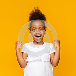 Cute black girl celebrating success, clenching fists