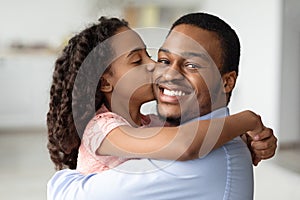 Cute black girl kissing her smiling father, closeup