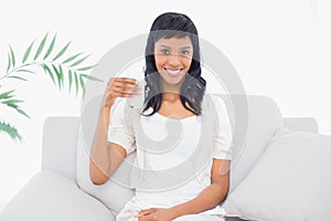 Cute black haired woman in white clothes holding a glass of water