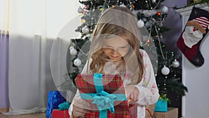 Cute blond 8 years old girl in her pajamas opens present box