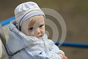 Cute blond baby wearing blue hat and jacket outdoors