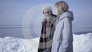 Cute blond bearded man walking with pretty woman holding hands. Amazing view of a snowy North or South Pole on the