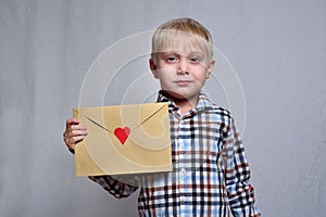 Cute blond boy with an envelope with a red heart. Congratulations, Valentine`s Day. White background