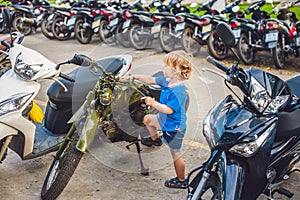Cute blond boy looking at vintage motorcycle eatables new motorbike