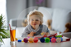 Cute blond child, boy, playing with play doh modeline at home, making different objects