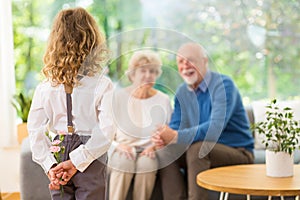 Cute blond child standing with flowers behind her back on the grandparent`s day