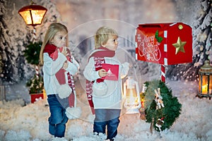 Cute blond children, boy and girl, siblings, posting Christmas letter to Santa Claus, winter day